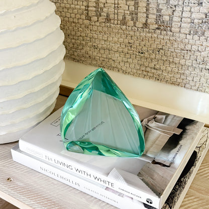 Green glass sculpture displayed on shelf in minimalist modern interior