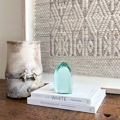 Green glass sculpture displayed on shelf in minimalist modern interior