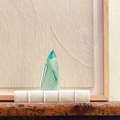 Contemporary emerald green glass sculpture reflecting light with fluid design