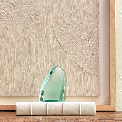 Abstract green glass sculpture with faceted crystal design on white base, modern home decor