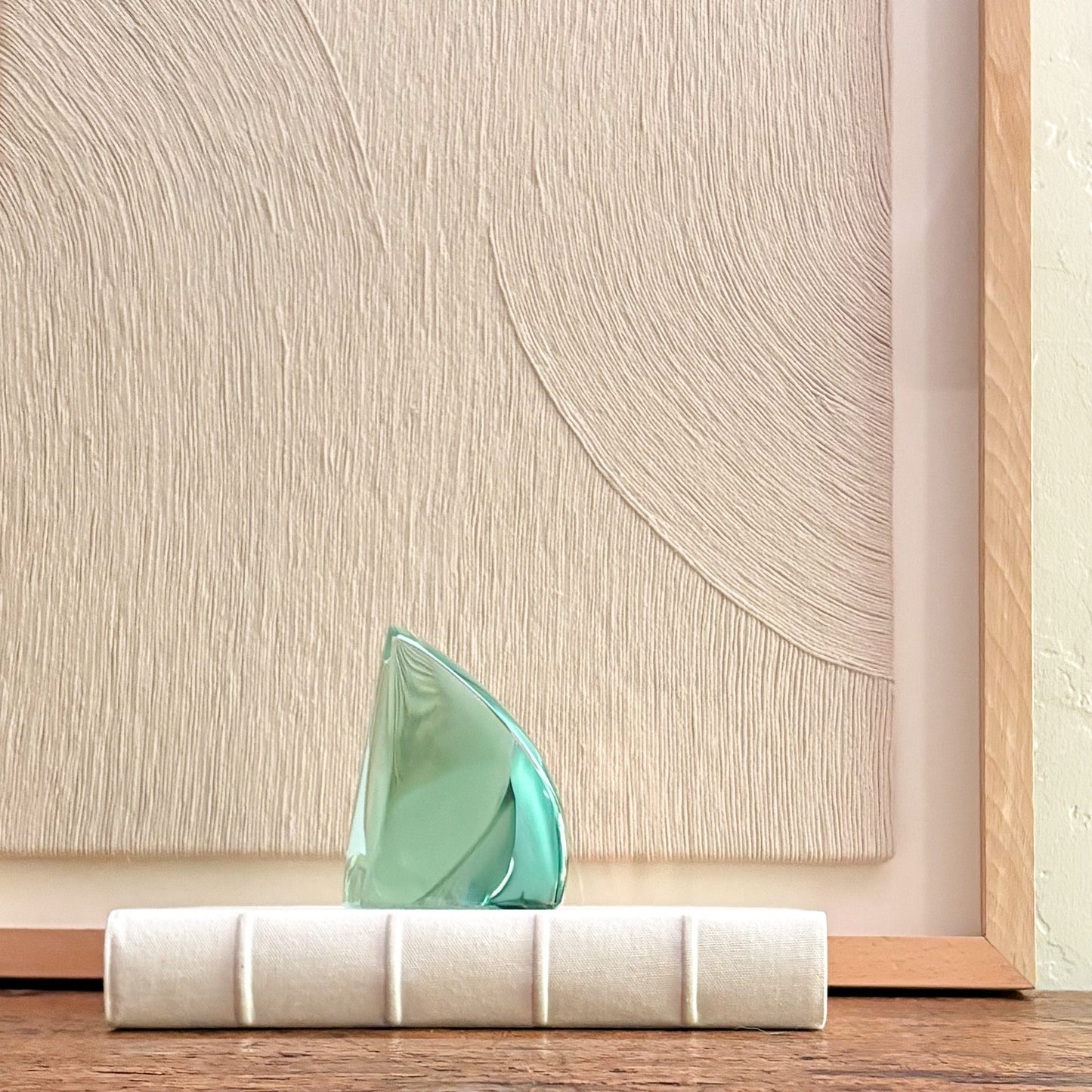 Contemporary green glass sculpture reflecting light with fluid design