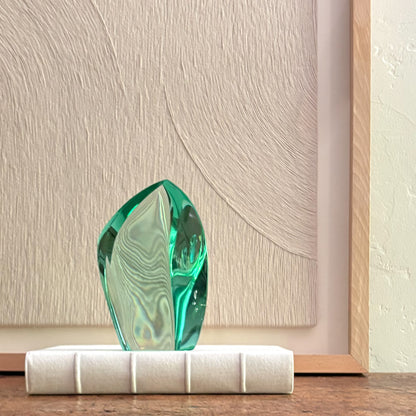 Abstract green glass sculpture with faceted crystal design on white base, modern home decor