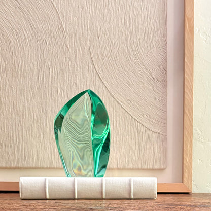 Unique green glass art piece with swirling design and reflective texture