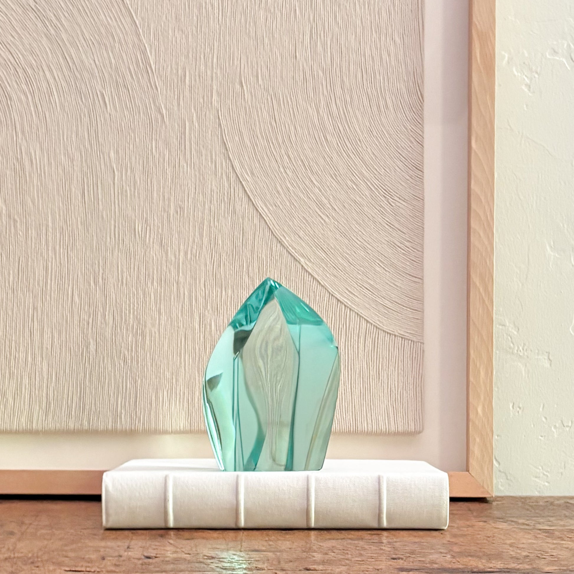 Abstract green glass sculpture with faceted crystal design on white base, modern home decor