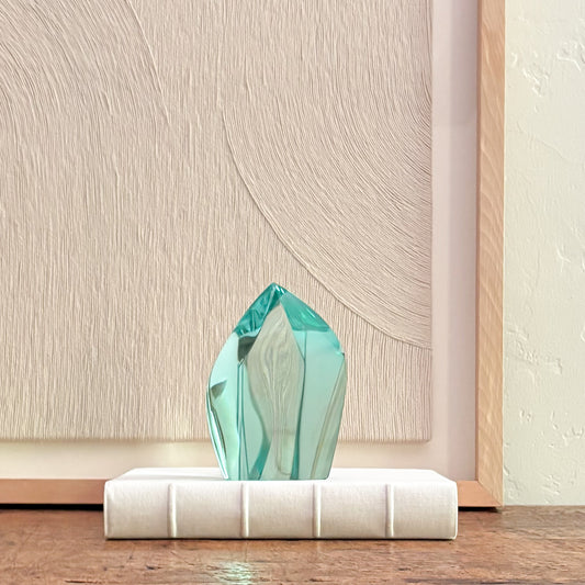 Abstract green glass sculpture with faceted crystal design on white base, modern home decor