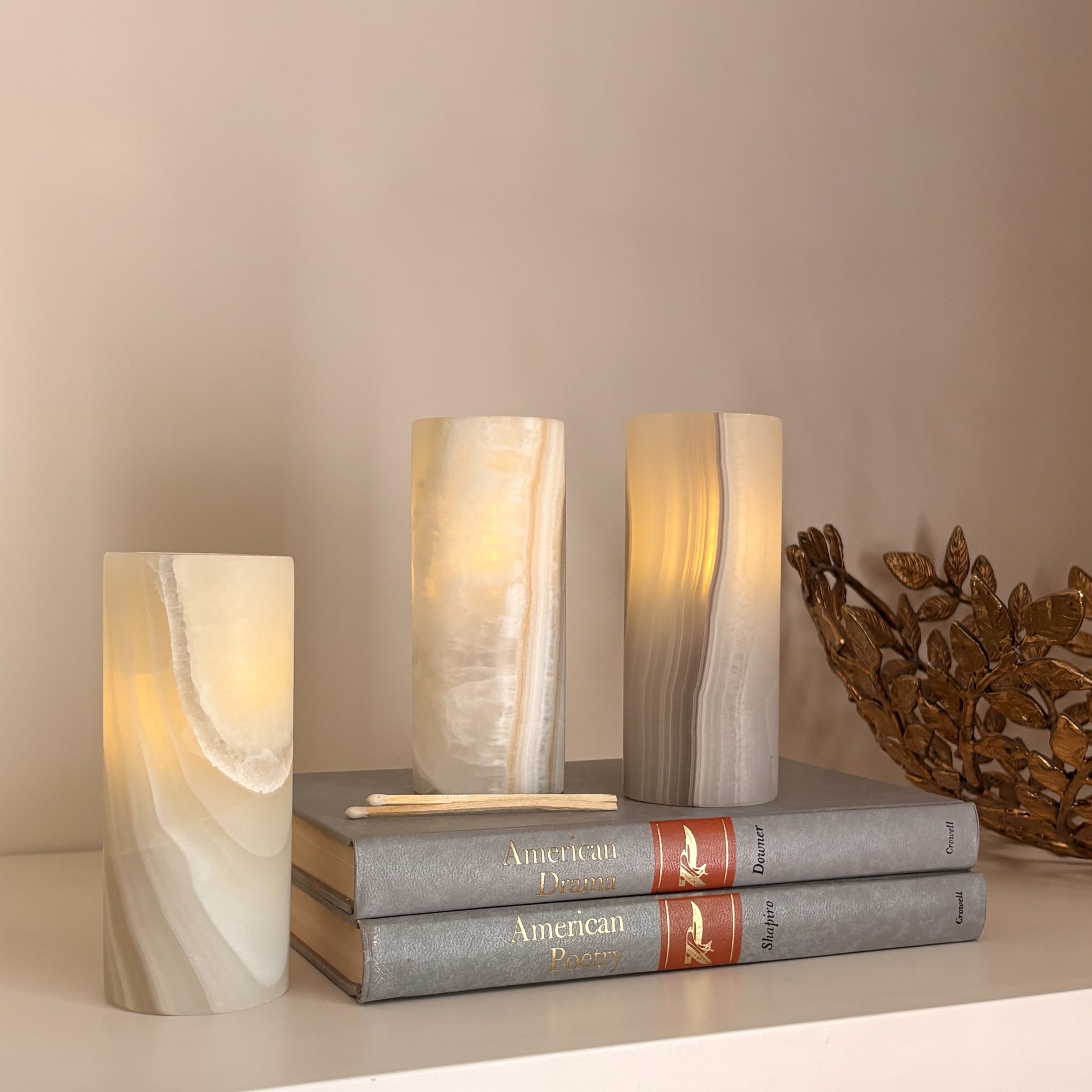 Luxury grey aragonite tealight candle holders styled on stacked books with warm ambient glow