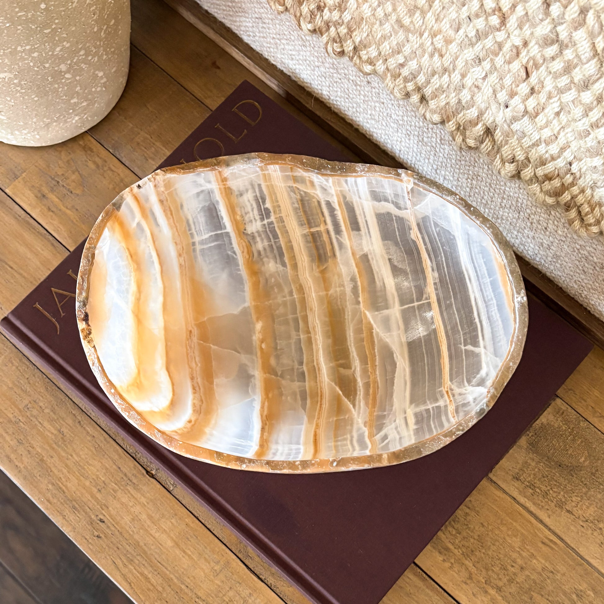 Decorative hand carved amber onyx bowl made from natural gemstone with translucent golden and cream banding.