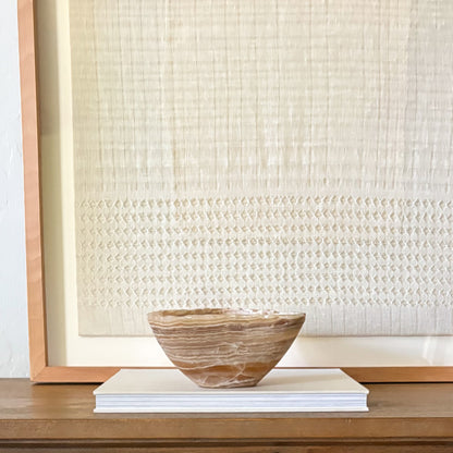 Decorative amber onyx bowl carved by hand with natural banded stone texture