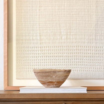 Artisan carved amber onyx bowl featuring warm honey and cream patterns