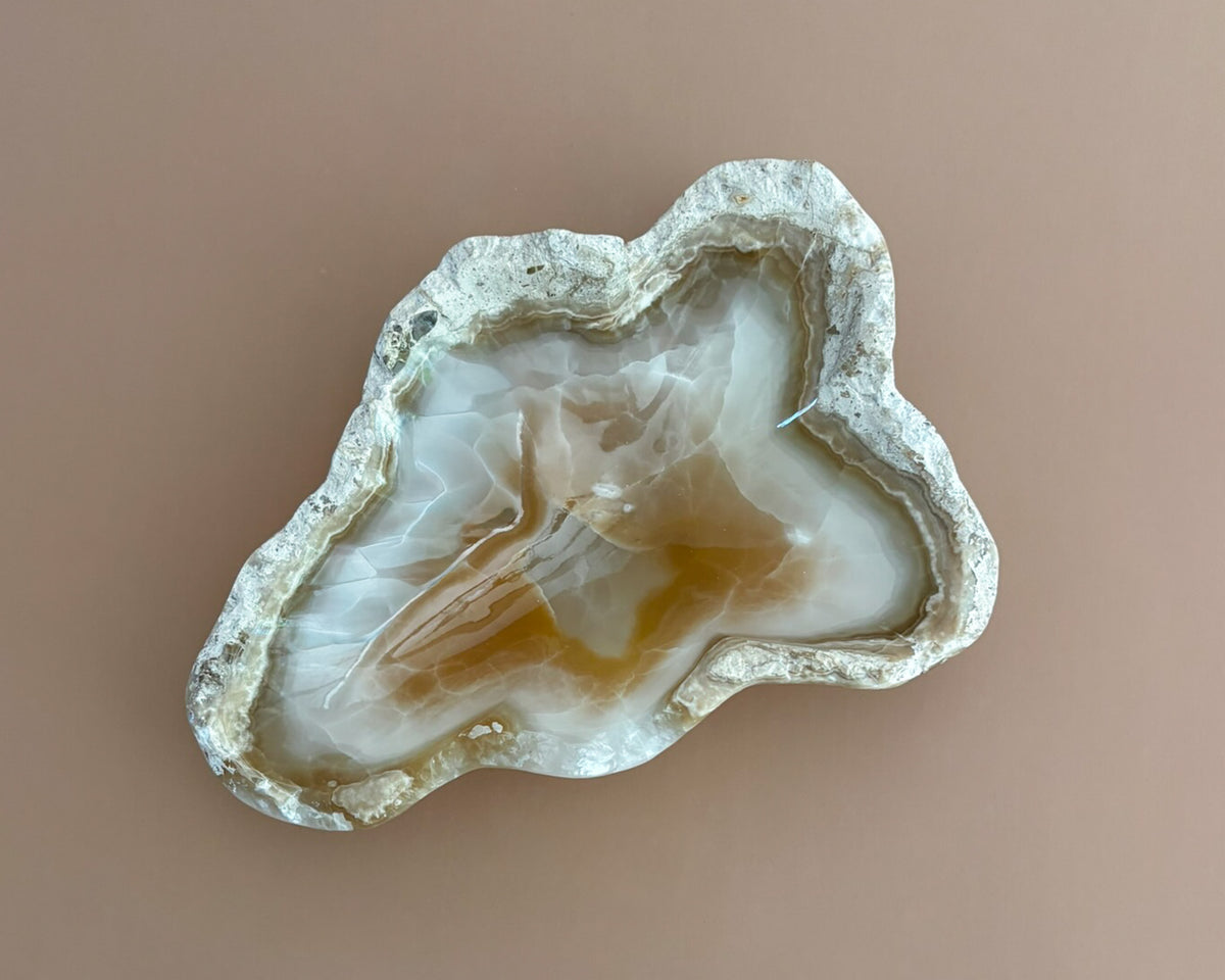 Decorative amber onyx bowl with distinctive natural banding and translucent honey-colored tones, hand-carved from solid stone