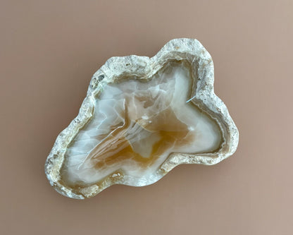 Decorative amber onyx bowl with distinctive natural banding and translucent honey-colored tones, hand-carved from solid stone