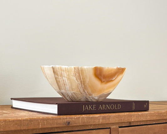 Hand-carved amber onyx bowl featuring warm golden tones and distinctive natural stone banding.