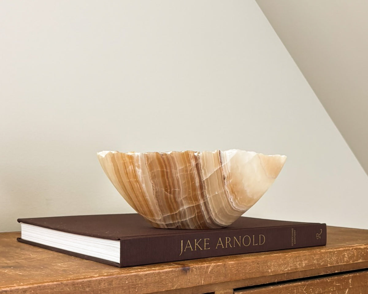 Hand-carved amber onyx bowl featuring warm golden tones and distinctive natural stone banding.