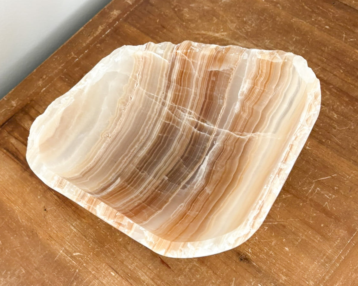 Close-up of a hand-carved amber onyx bowl highlighting its natural banding and polished stone surface.