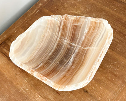 Close-up of a hand-carved amber onyx bowl highlighting its natural banding and polished stone surface.