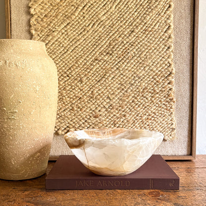 Decorative onyx bowl on a book with a textured wall in the background