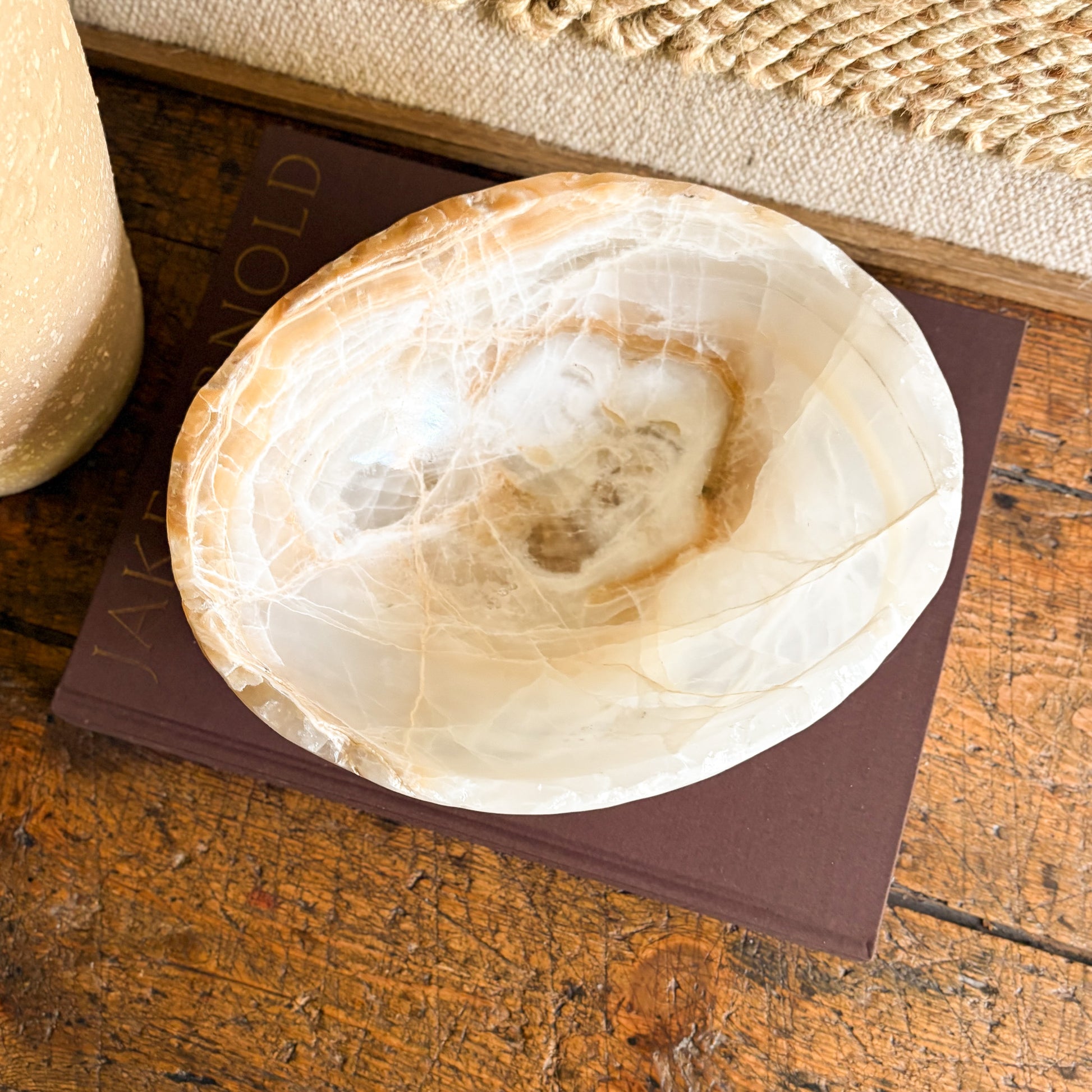 Decorative onyx stone bowl on a textured surface with a book underneath