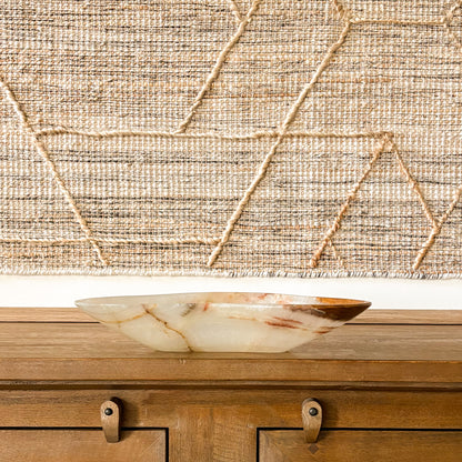 Polished brown onyx bowl with natural veining displayed on rustic wooden table