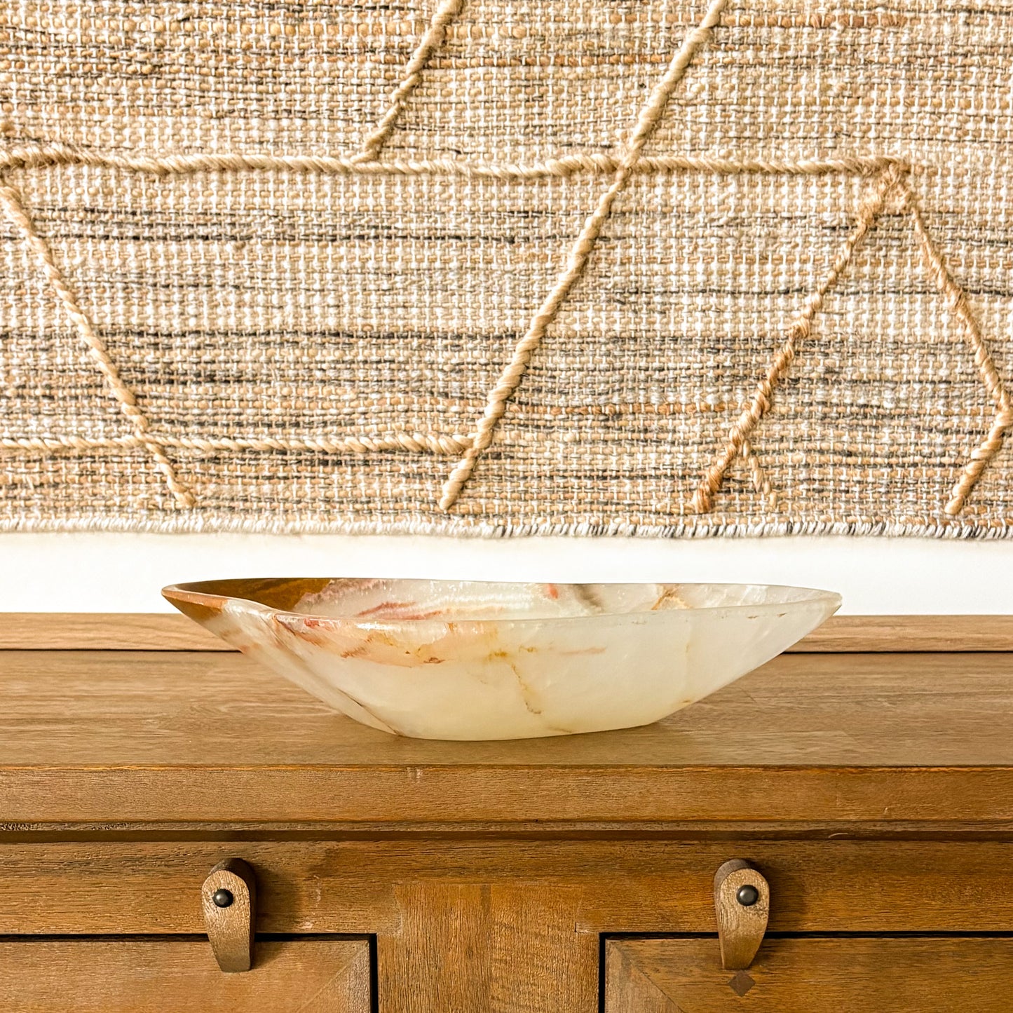 Handcrafted onyx stone bowl in neutral home decor setting with woven wall art