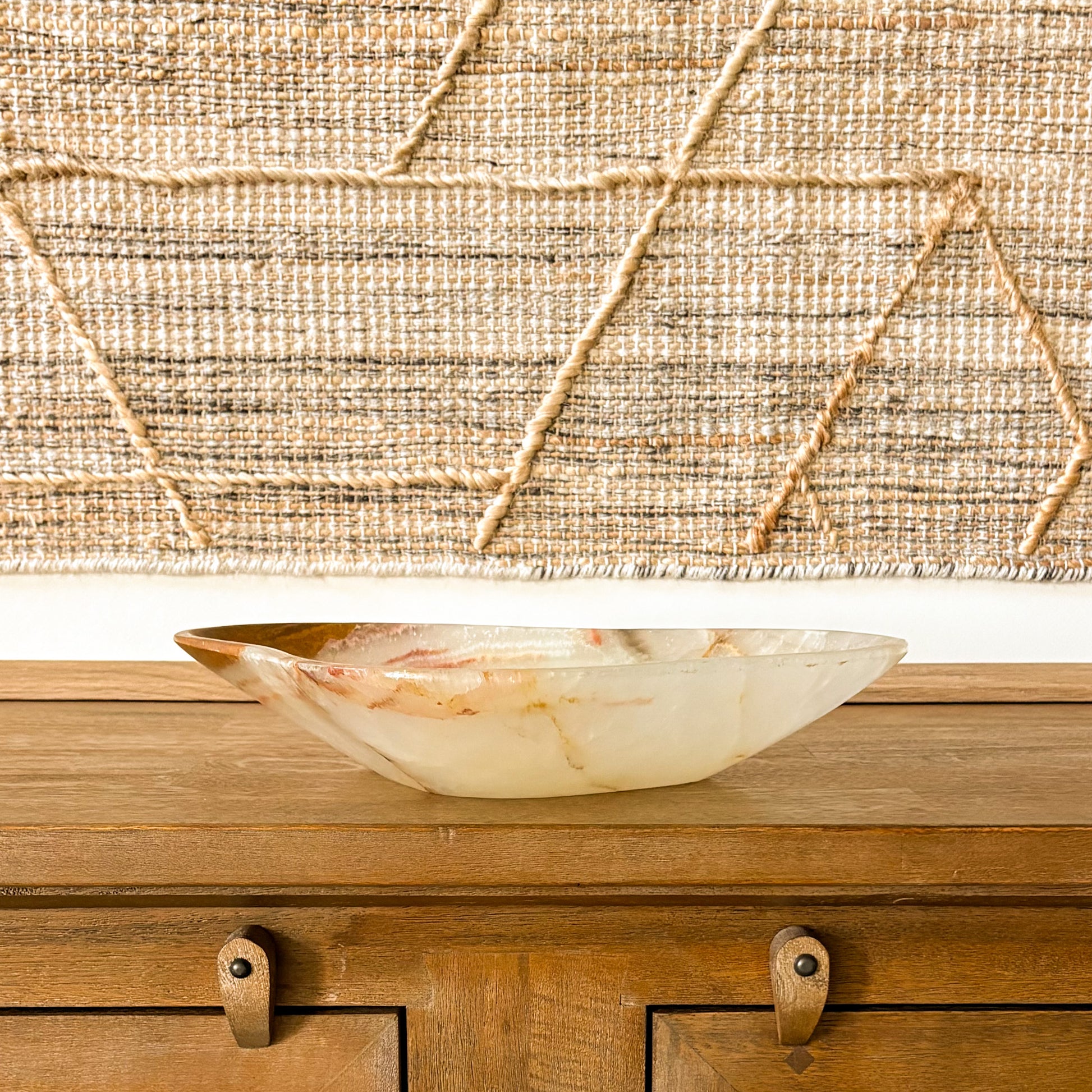 Handcrafted onyx stone bowl in neutral home decor setting with woven wall art