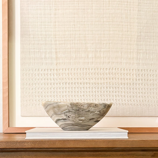 Hand-carved grey onyx bowl styled on a console table in a modern organic living room.