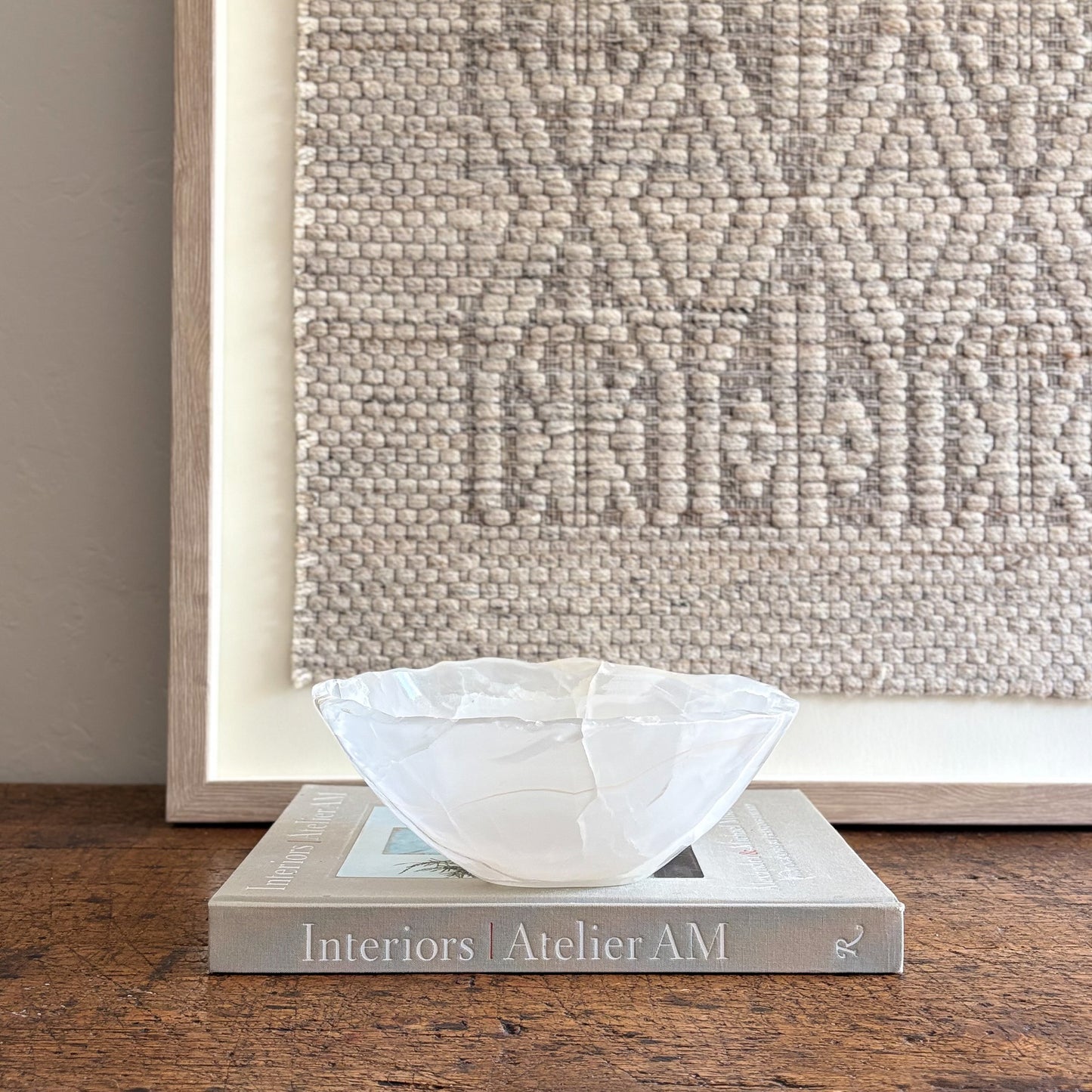 White decorative onyx bowl on a book with a textured wall in the background