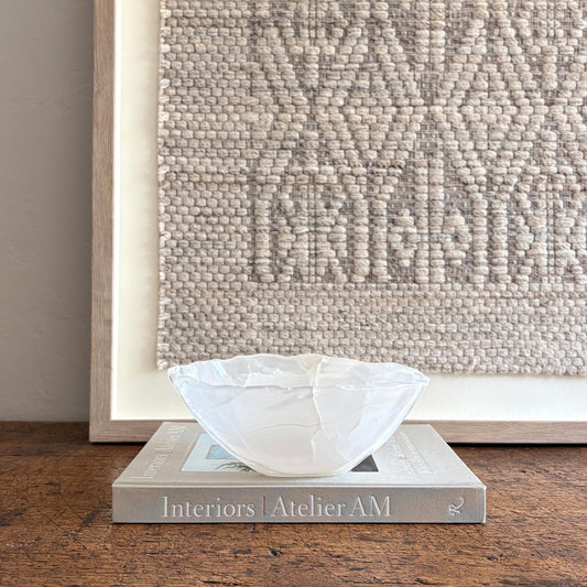 White decorative onyx bowl on a book with a textured wall in the background