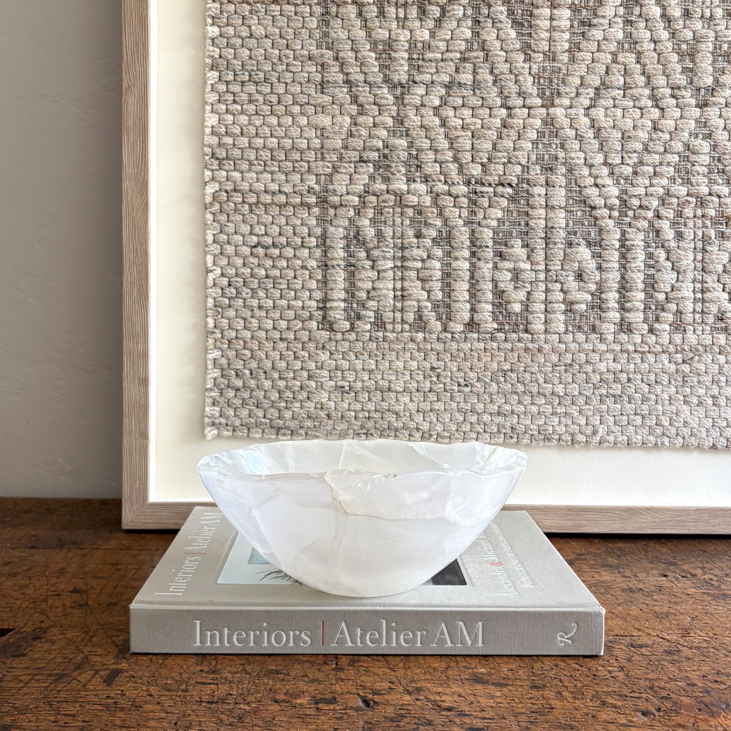 White accent bowl on a book with a textured wall in the background