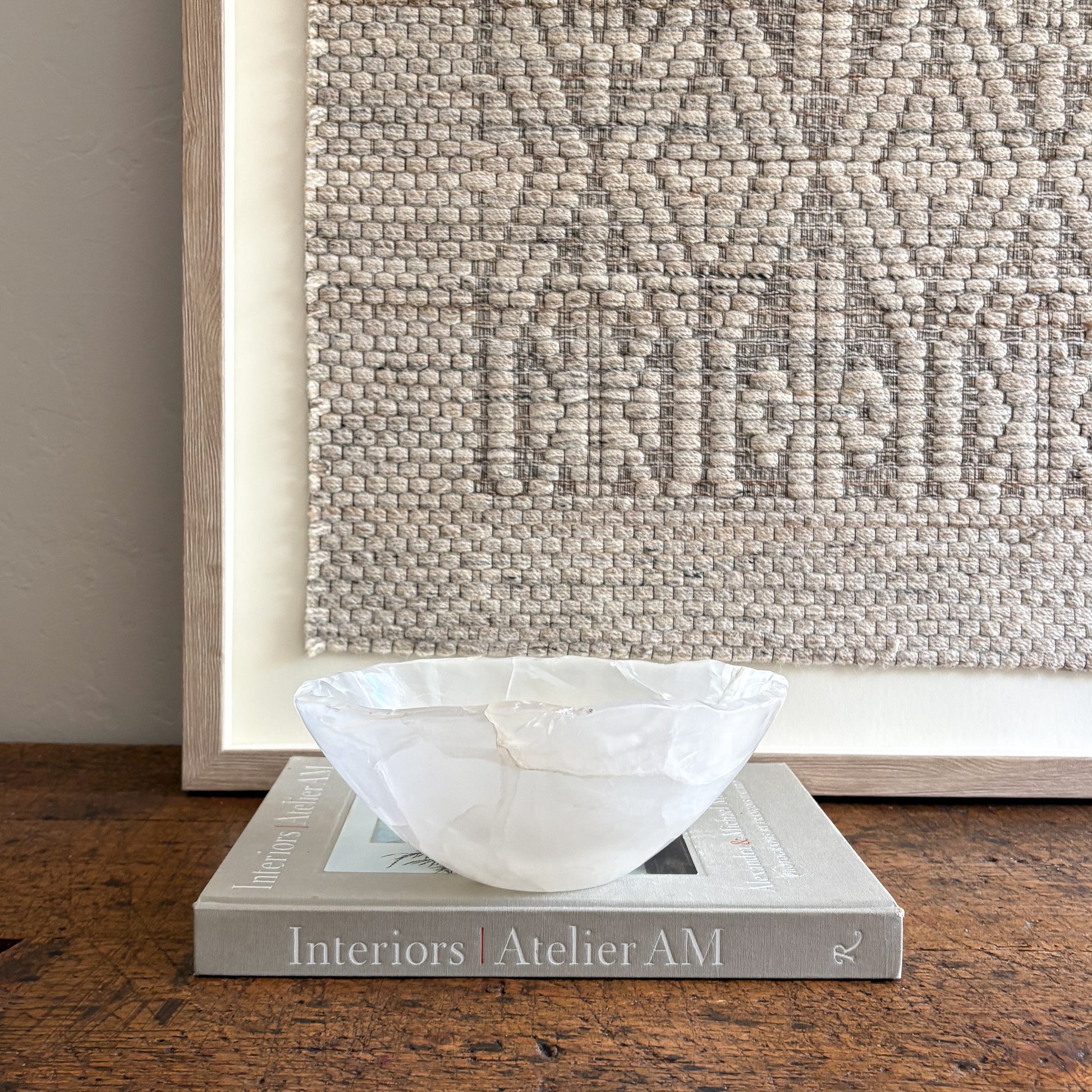 White accent bowl on a book with a textured wall in the background