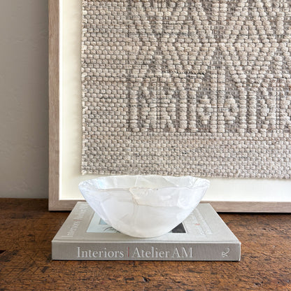 White accent bowl on a book with a textured wall in the background