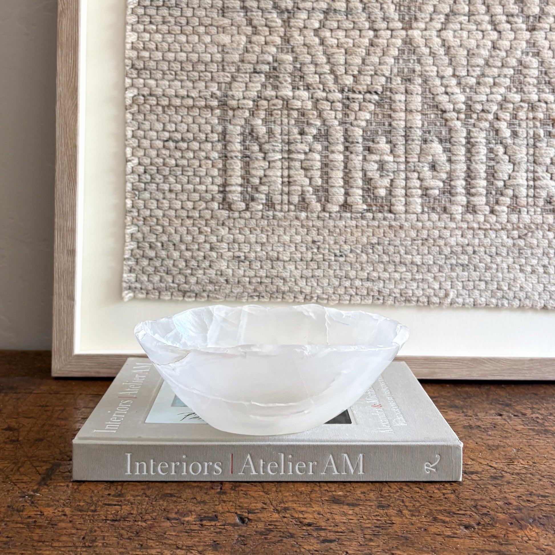 decorative onyx bowl on a book with textured wall art in the background