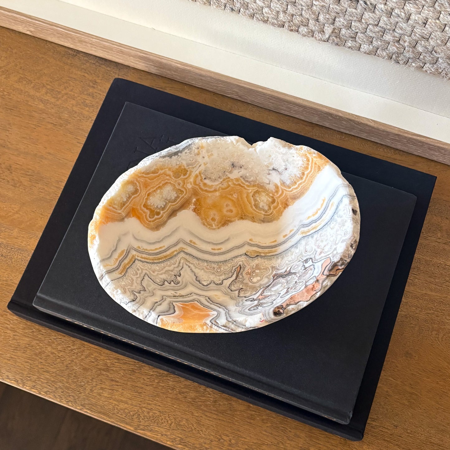 Natural zebra calcite gemstone bowl with gray and amber veining on wooden console