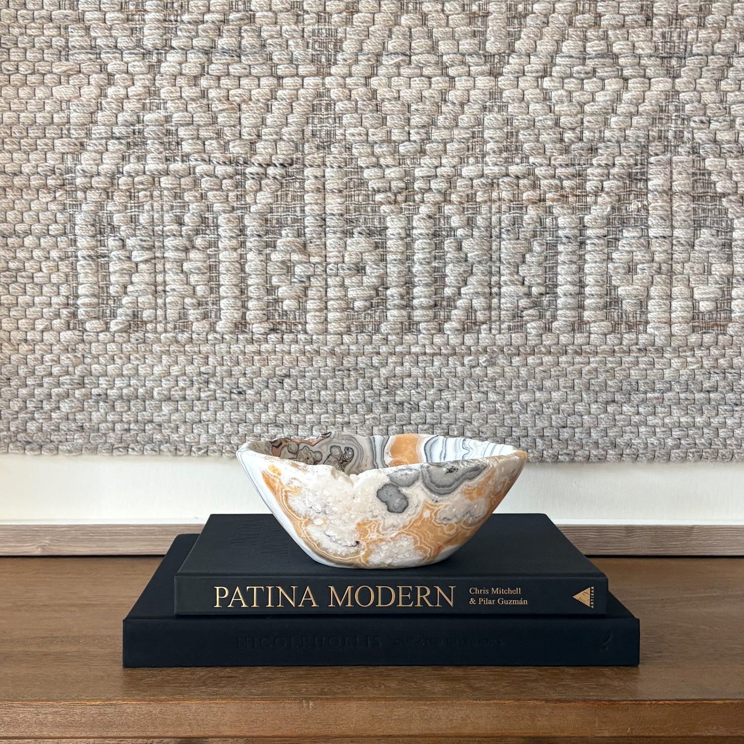 Polished zebra calcite stone bowl with dramatic striped pattern styled on coffee table books