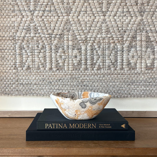 Polished zebra calcite stone bowl with dramatic striped pattern styled on coffee table books