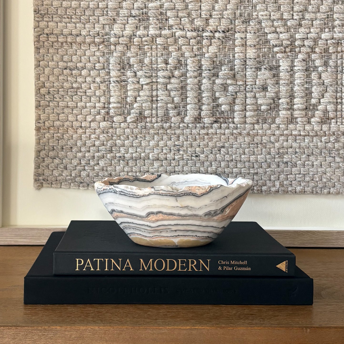 Polished zebra calcite stone bowl with dramatic striped pattern styled on coffee table books