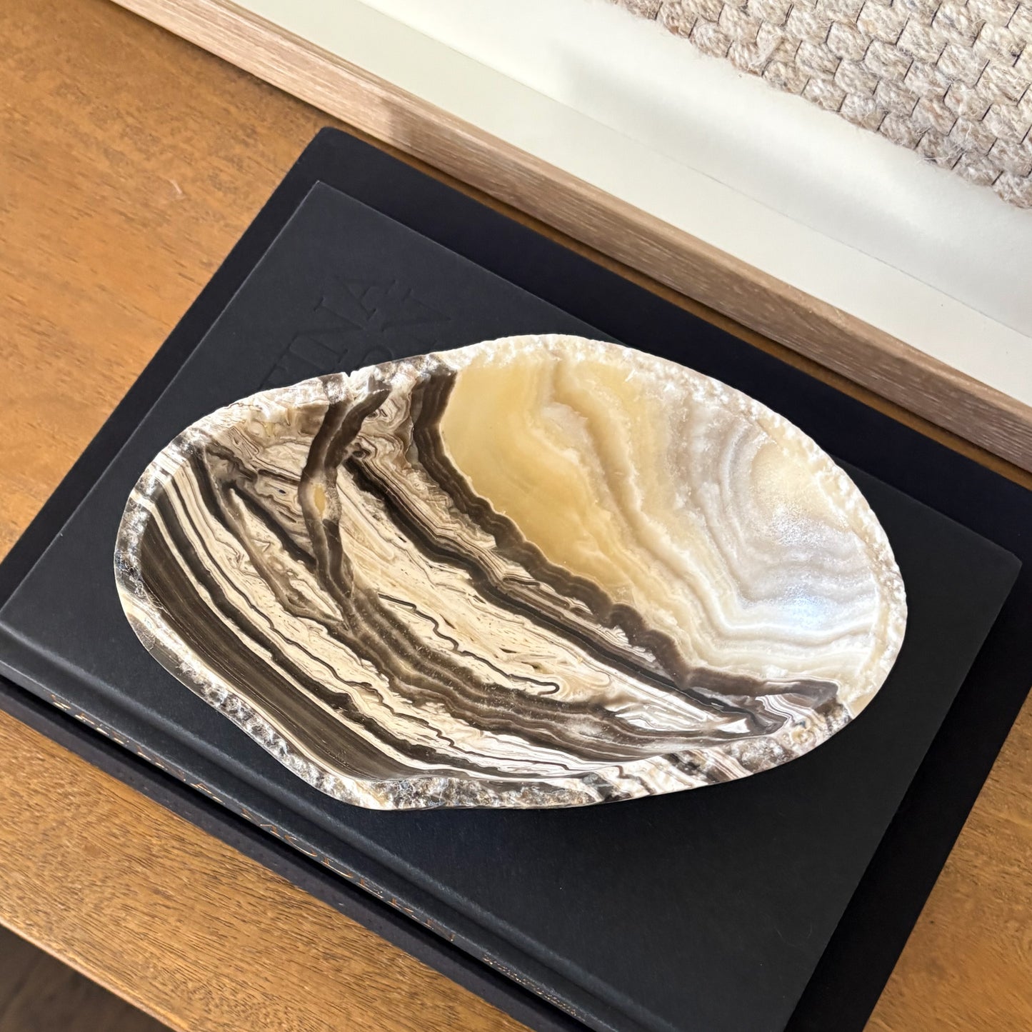 Natural stone zebra onyx bowl on wooden table with textured textile wall hanging