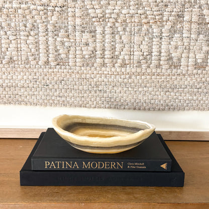 Small zebra onyx decorative bowl with natural striped stone pattern on wooden console