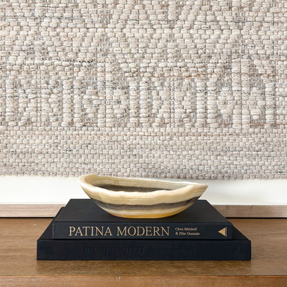 Natural stone zebra onyx bowl on wooden table with textured textile wall hanging