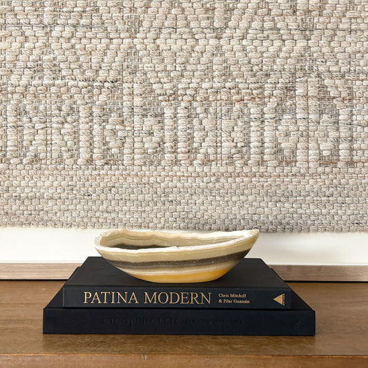 Hand carved zebra onyx bowl styled on Patina Modern book with neutral wall art backdrop