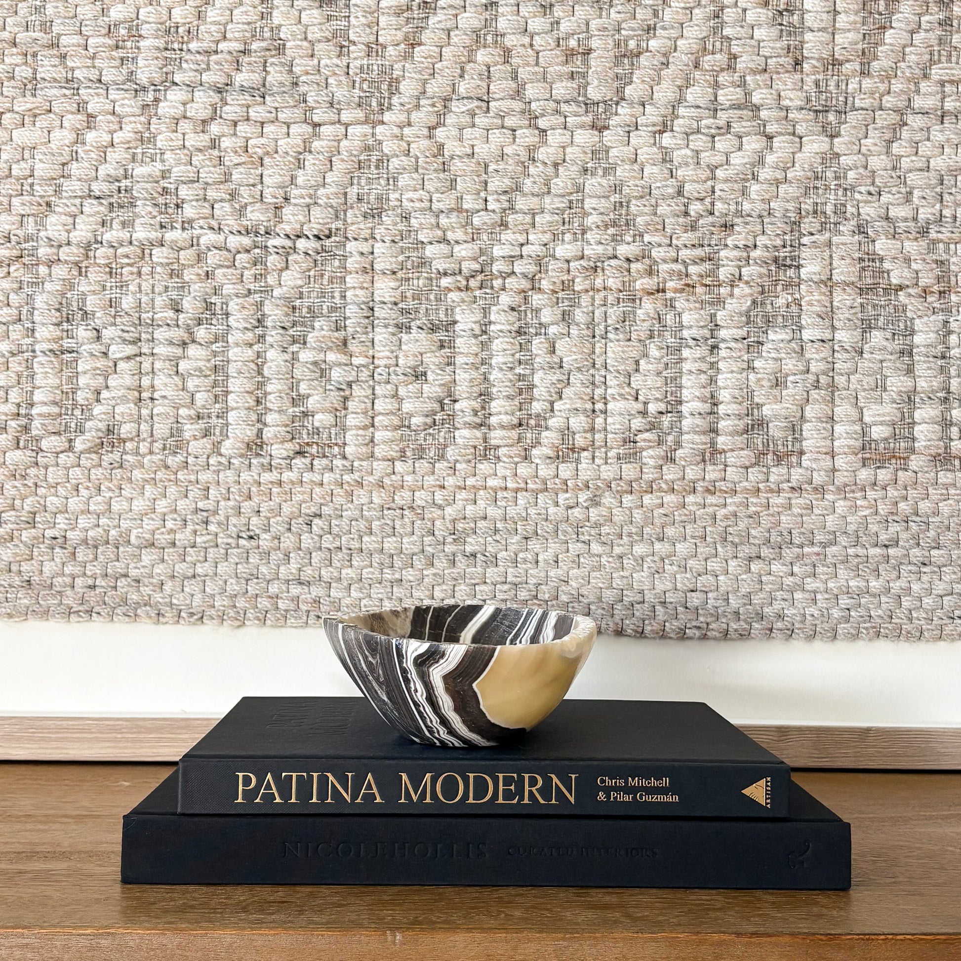 Natural stone zebra onyx bowl on wooden table with textured textile wall hanging