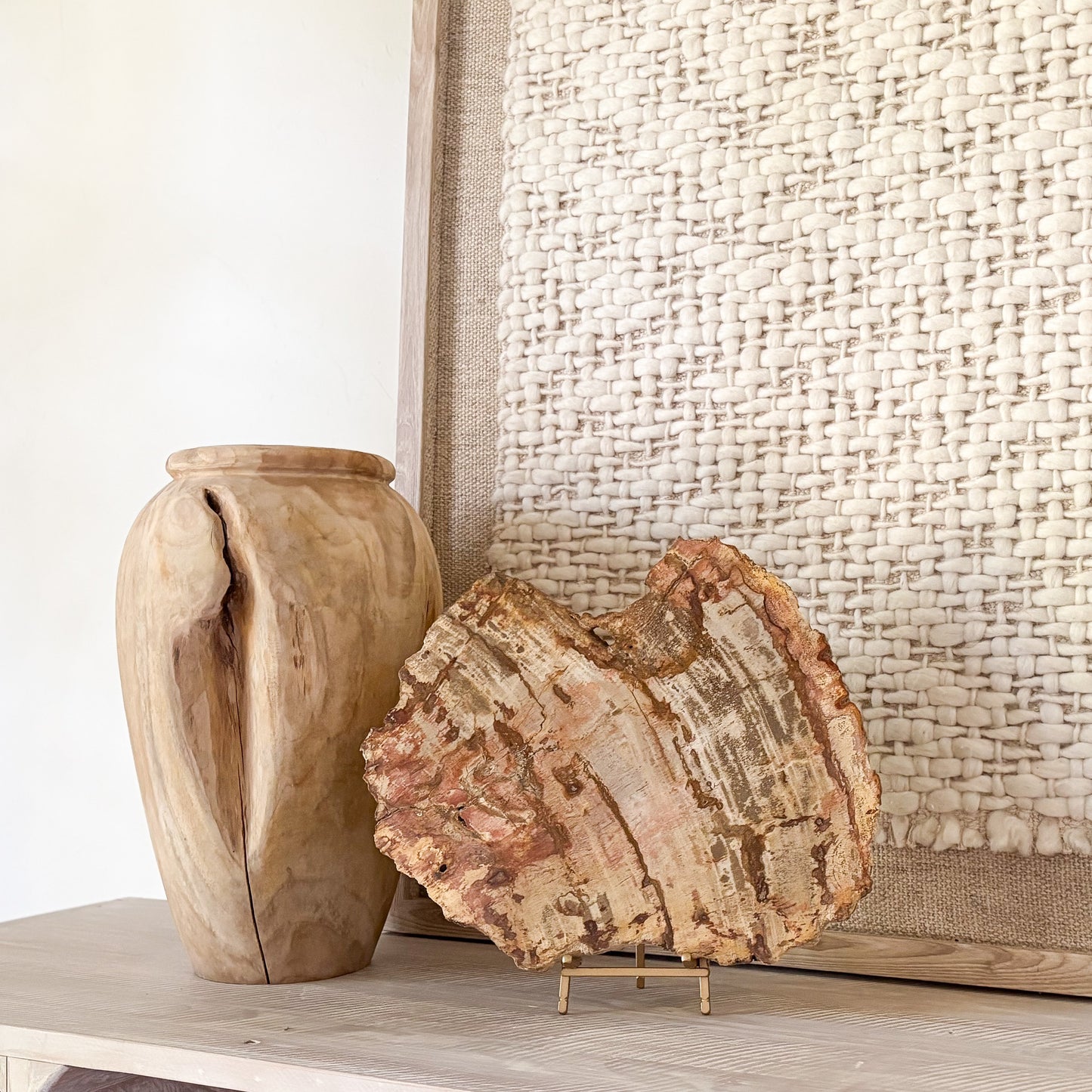Wooden vase and petrified wood on a surface with a textured wall in the background