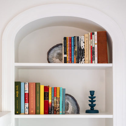 Large blue Brazilian agate bookend pair displayed on white built-in bookshelf with colorful books and modern decor.