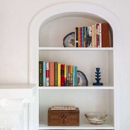 Large blue agate geode bookends on white shelving, styled with books and minimalist home decor accents.