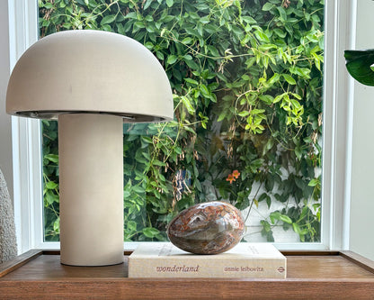 Large decorative Ibis Jasper egg displayed on a coffee table book beside a modern table lamp