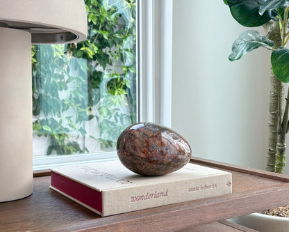 Decorative Ibis Jasper stone egg with unique natural veining and earthy colors for shelf styling