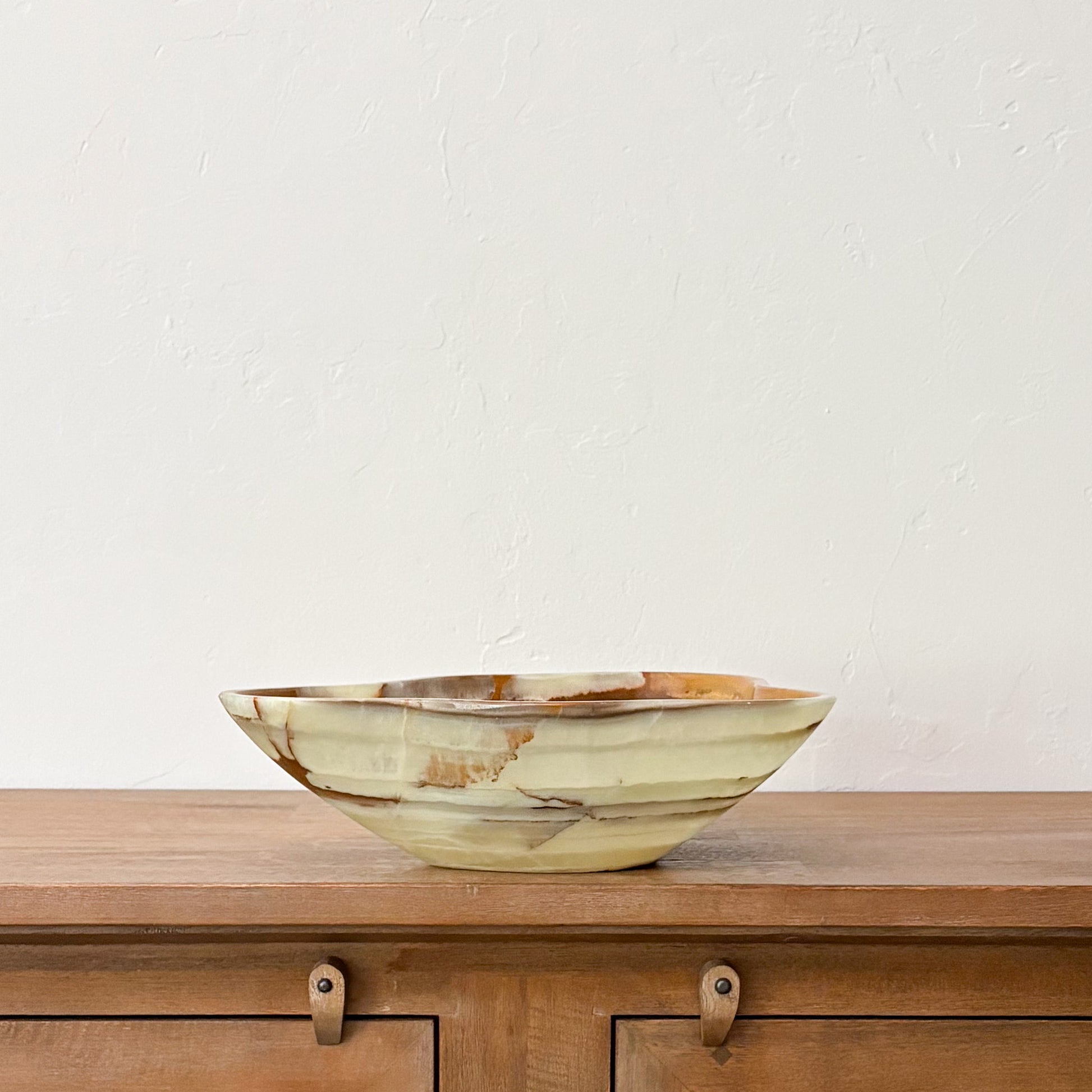 Decorative polished green onyx centerpiece bowl featuring organic freeform edges and earthy natural stone patterns.