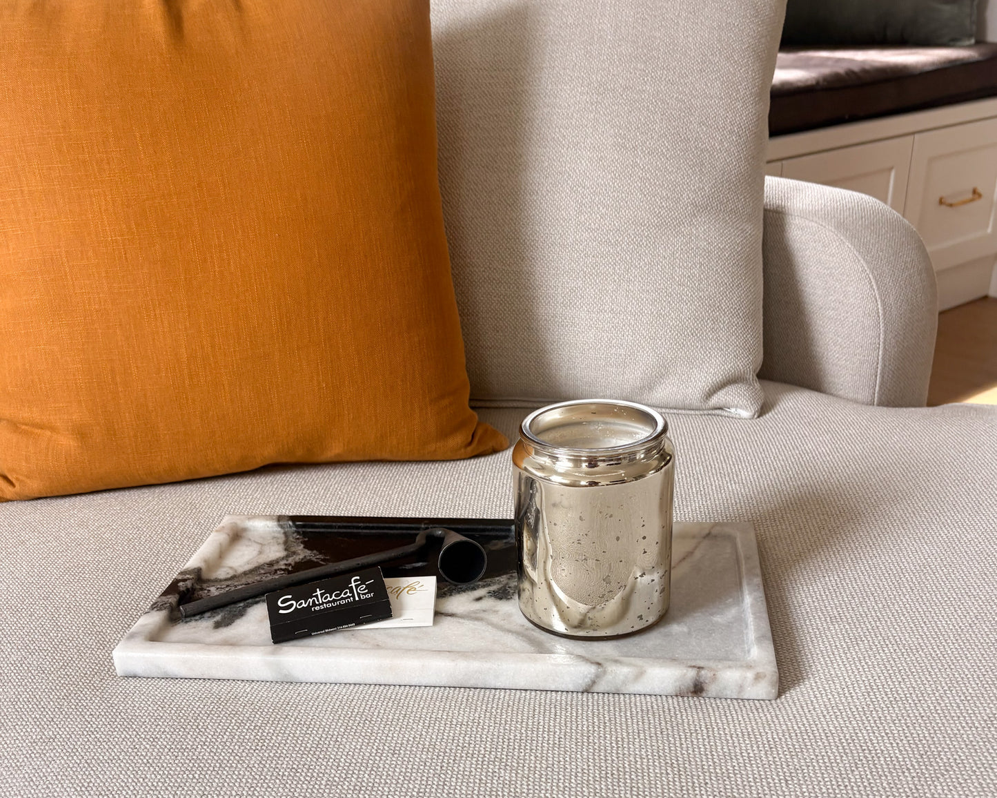 Black and white Panda marble tray styled on a neutral upholstered ottoman