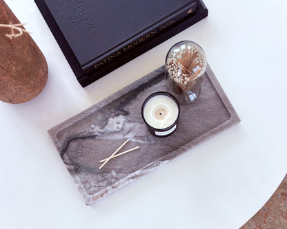Large natural Pocahontas marble tray featuring organic gray veining, displayed with a candle and match holder in a modern living room.