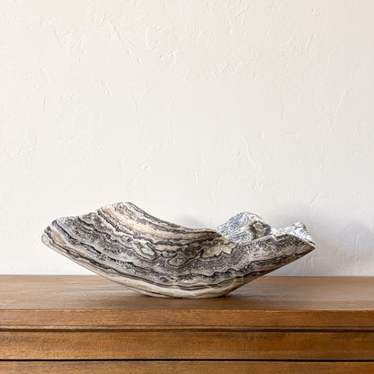 Large hand-carved zebra onyx bowl with dramatic natural banding in cream, gray, and black displayed on a wooden table.
