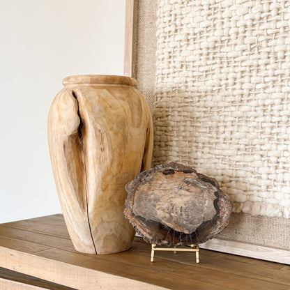 Ancient petrified wood fossil slab from Madagascar on console table with a teak wood vase